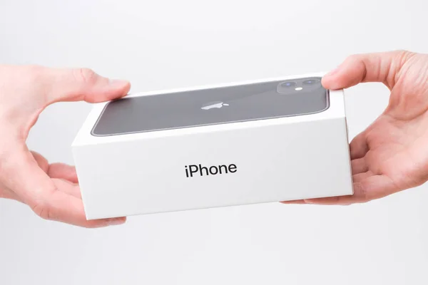 Man and woman hand holding a box with black iPhone 11 on the grey background, December 2020, San Francisco, USA — Foto Stock