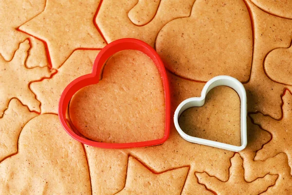 Massa para fazer biscoitos em forma de coração no Dia dos Namorados. Pastelaria caseira. Moldes de cozimento de plástico vermelho e verde. — Fotografia de Stock