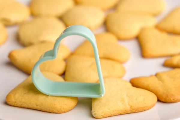 Zelfgemaakte koekjes voor St. Valentijnsdag met groene plastic bakvorm. — Stockfoto