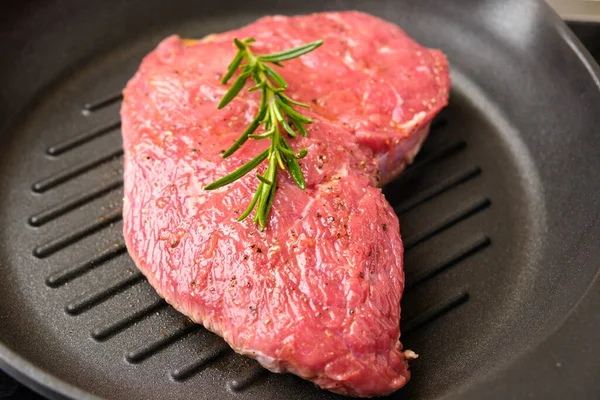 Roh frisches Rindersteak mit Rosmarin auf einer Grillpfanne. — Stockfoto