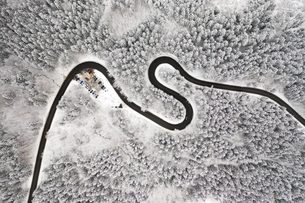 Estrada curva em forma de S na vista aérea da floresta de inverno. Estrada sinuosa vazia cercada por pinheiros altos. — Fotografia de Stock