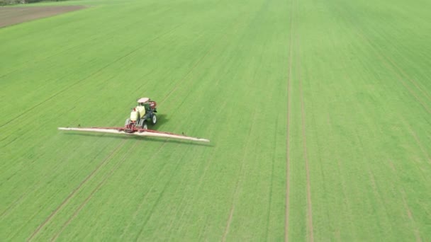 Aerial footage of tractor fertilizing with chemicals a green agriculture wheat field. — Stock Video