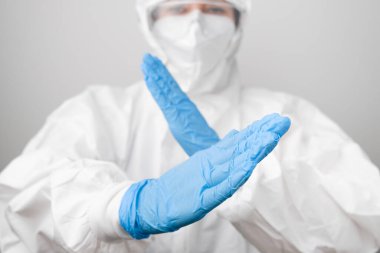 Korunaklı koruyucu PPE kıyafetli bir doktor ve koronavirüs, Sars-Cov-2, mavi lastik eldivenli Covid-19 maskeli koruyucu maske dövüşleri..