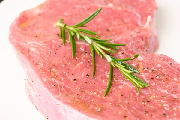 Rohes Rindersteak mit Rosmarinzweig und auf weißem Hintergrund isolierten Arten. — Stockfoto