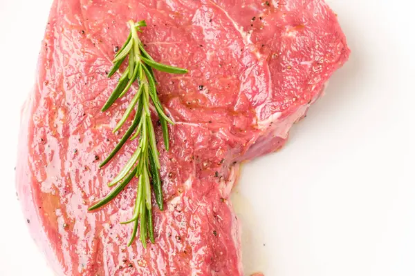 Rohes Rindersteak mit Rosmarinzweig und auf weißem Hintergrund isolierten Arten. — Stockfoto