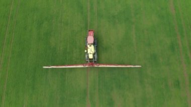 Tarım traktörünün tarlayı sürdüğü ve yeşil buğday tarlası püskürttüğü hava manzarası. Böcek ilacı, ot ilacı ya da böcek ilacı ile ekinlerin korunması