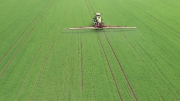 Aerial footage of tractor fertilizing with chemicals a green agriculture wheat field. — Stock Video