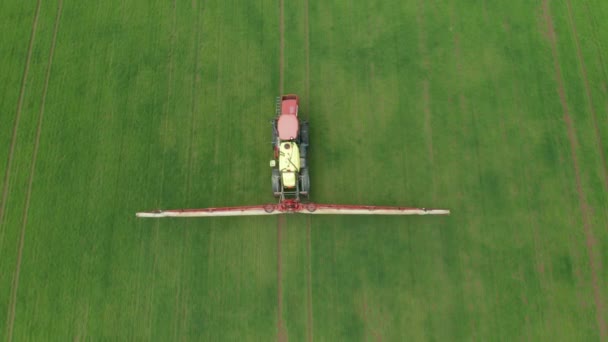 Vista aérea del tractor agrícola arando y rociando el campo de trigo verde. Protección de cultivos mediante la aplicación de plaguicidas, herbicidas o insecticidas — Vídeos de Stock
