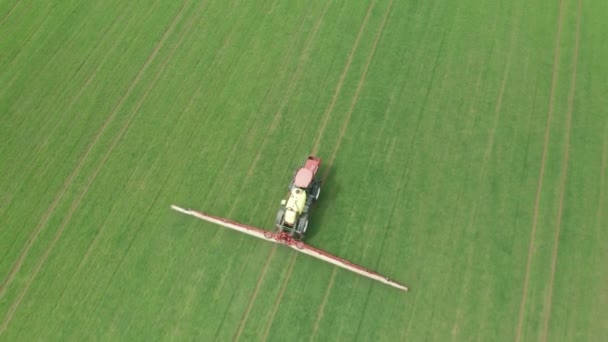 Luchtopname van tractor bemesting met chemicaliën een groen tarweveld voor de landbouw. — Stockvideo