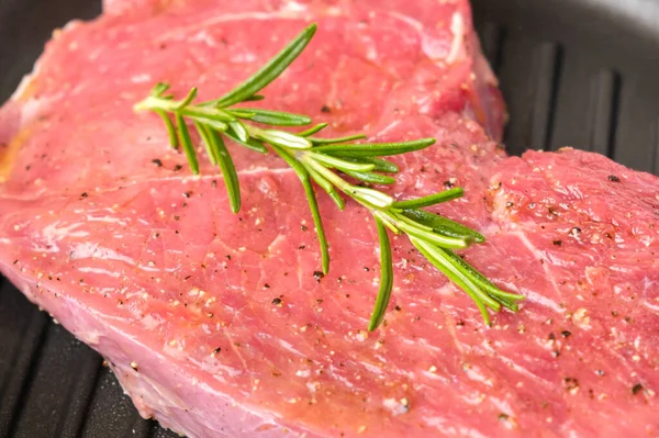 Roh frisches Rindersteak mit Rosmarin auf einer Grillpfanne. — Stockfoto