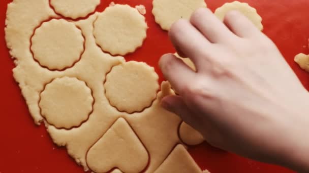 Kvinnliga händer tar kakor i form av hjärta och runda för St. Alla hjärtans dag med röd plast mögel på den röda silikon bakning matta. — Stockvideo