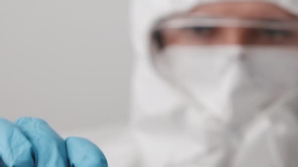 Dokter in beschermend pak, gezichtsmasker, veiligheidsgoogles en rubberen handschoenen demonstreren vaccin tegen coronavirus. Ontwikkelen en testen van Covid 19-vaccin — Stockvideo