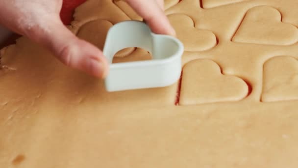 Fazer biscoitos em forma de coração para o dia de São Valentim usando molde de plástico no tapete de cozimento de silicone vermelho. — Vídeo de Stock