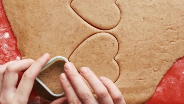 赤いシリコーンベーキングマット上のプラスチック金型を使用して聖バレンタインデーの心の形でクッキーを作る. — ストック動画