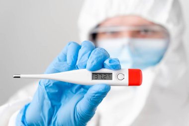 Doktorların elinde 37,2 santigrat dereceli dijital ya da elektronik termometre. Koruyucu PPE kostümlü doktor ya da hemşire, yüz maskesi, güvenlik Google 'ı ve lastik eldiven sıcaklığı gösterir