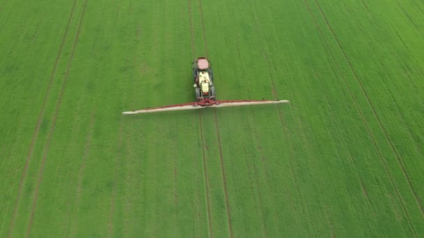 Aerial view of farming tractor plowing and spraying green wheat field. Protection of crop with applying of pesticides, herbicides or insecticides — Stock Video