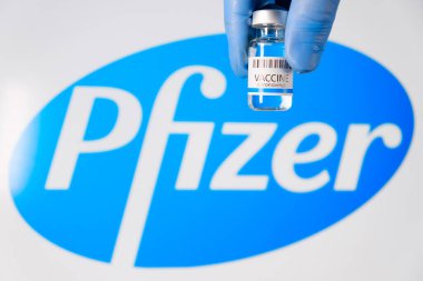 Doktorların şişesindeki Pfizer aşısı logonun arka planında lastik eldivenler verdi, Ocak 2021, San Francisco, ABD