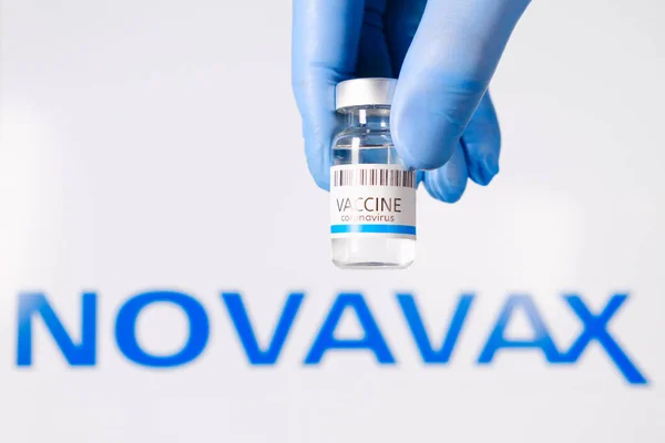 Novavax vaccin i flaskan i läkare hand i gummihandskar på bakgrunden av logotypen, Januari 2021, San Francisco, USA — Stockfoto