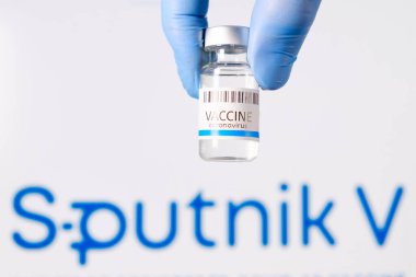 Doktorların şişesindeki Sputnik V aşısı logonun arka planında lastik eldivenler verdi, Ocak 2021, San Francisco, ABD