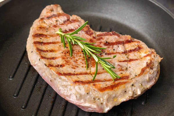 Fried beef steak in the grill pan with rosemary. Healthy dinner concept