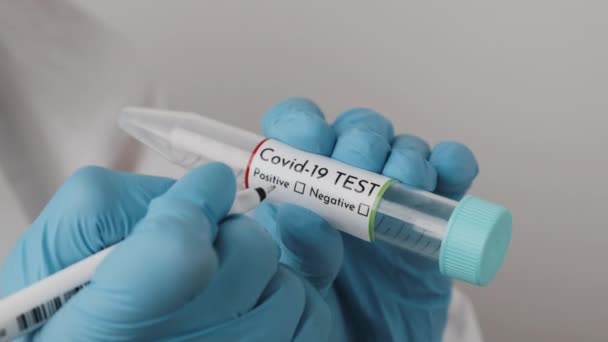 Pekerja laboratorium mengisi koronavirus positif pada tabung tes sarung tangan karet biru — Stok Video