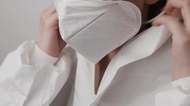 Coronavirus hastalarıyla çalışmadan önce biyolojik tehlike önleyici PPE giysiyi ve FFP2 solunum cihazını kapatan bir laboratuvar çalışanı ya da doktor.. 