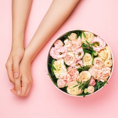 Kadınların yanındaki güzel çiçeklerle dolu kutu. Siyah arka planda fotokopi alanı olan eller. Güzellik salonu kartı konsepti. 8 Mart için hediye, Anneler Günü, Sevgililer Günü