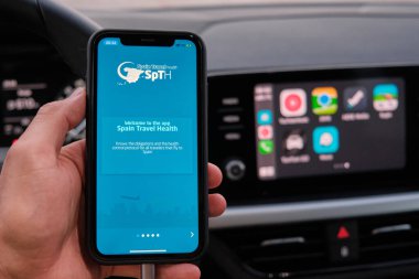 İspanya Seyahat Sağlığı uygulaması, Apple Carplay 'in navigasyon ya da haritalarının uygulandığı araç gösterge panelinin arka planında iphone ekranında. Ocak 2021, Prag, Çek Cumhuriyeti