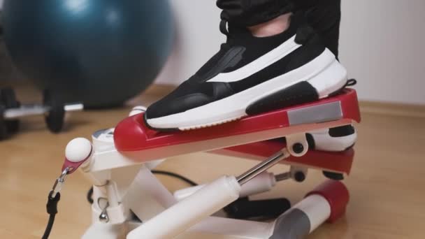 Piedi da donna da vicino in sneakers training sul twist stepper con display digitale ed espansori gengivali a casa durante l'isolamento. — Video Stock