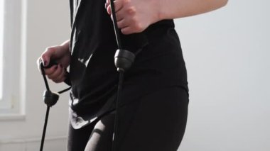 Siyah spor giysili bir kadın, basamakları genişleterek egzersiz yapıyor. Evde kardiyo eğitimi. Tecrit sırasında evde çalışma