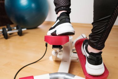 Spor ayakkabılı kadın ayaklarının arka planı kilitlenme sırasında evdeki döner basamaklı ya da merdiven basamaklı makinede egzersiz yapıyor. Formda kal. Evde kardiyo. 