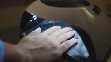 Ultraviyole ışığı olan kadın eli ya da tırnaklarında kurutulmuş jel cilası. Mükemmel manikür.. 