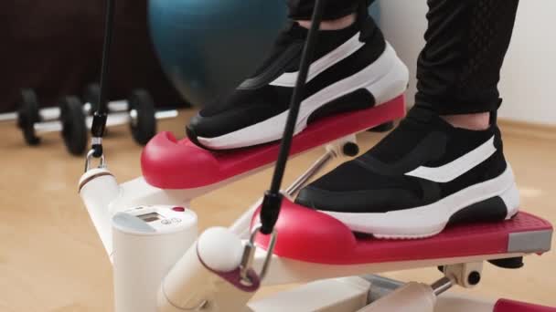 Pohled zepředu na ženské nohy na přestupní stroj dělá cvičení doma — Stock video