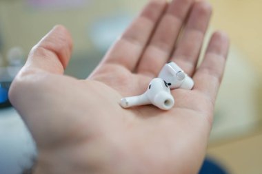 Kadın avucundaki bluetooth kulaklıkları ya da kulaklıkları kapat.