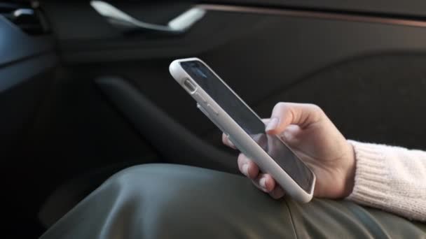 Cerca de las mujeres mano desplazándose por su teléfono inteligente en el coche. — Vídeos de Stock