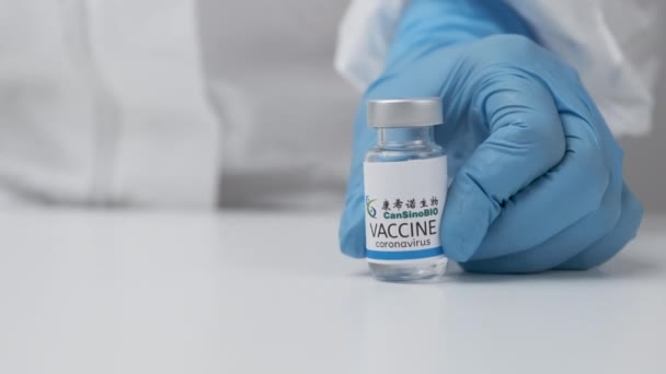 CanSino BIO vacina contra coronavírus e seringa para injeção em mão de trabalhador de saúde em luvas de borracha e terno de proteção, março de 2021, São Francisco, EUA — Vídeo de Stock