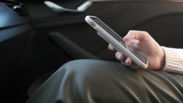 Cerca de las mujeres mano desplazándose por su teléfono inteligente en el coche. — Vídeo de stock