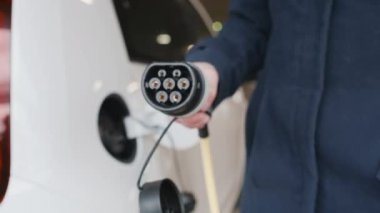  Kadınlar park yerinde şarj etmek için elektrikli bir arabanın fişini takıyor.