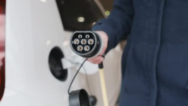 Vrouwen hand pluggen in een elektrische auto op te laden op de parkeerplaats — Stockvideo