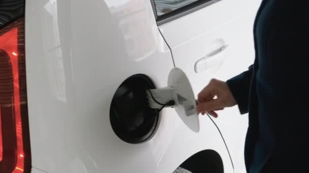 Zakelijke vrouw het invoegen van een lader in de elektrische auto op laadpunt in de parkeerplaats en ga weg — Stockvideo