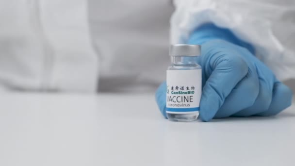 CanSino BIO вакцина проти коронавірусу та шприца для ін'єкції рук медичних працівників у гумові рукавички та захисний костюм, березень 2021 року, Сан-Франциско, США — стокове відео
