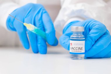 Coronavirus 'a karşı biyoilaç aşısı ve sağlık çalışanlarına enjeksiyon için şırınga kauçuk eldiven ve koruyucu giysi, Mart 2021, San Francisco, ABD