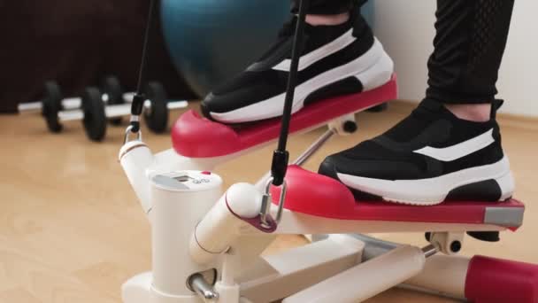 Close up woman foot in the black sneakers working out on the stepper at home — Stock Video