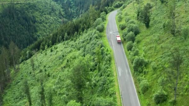 Letecký pohled na silnici s auty a kamionem v horách s vysokými zelenými jedlemi, listovníky, borovicemi nebo smrky. — Stock video