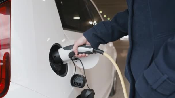 Vrouw hand ontkoppelde stroomkabel voeding op te laden elektrische of EV auto — Stockvideo