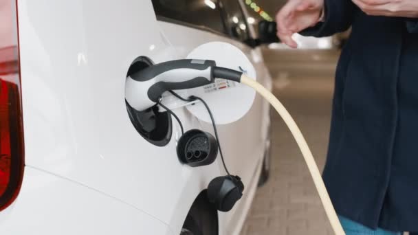 Mujeres desenchufar un coche eléctrico después de cargar en el aparcamiento — Vídeo de stock