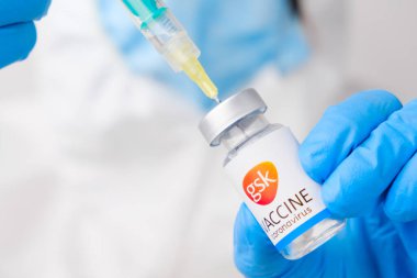 Sağlık çalışanı veya doktor tarafından şırıngaya alınan koronavirüs aşısı koruyucu eldivenler ve PPE giysisi ile GSK aşısı, Nisan 2021, San Francisco, ABD