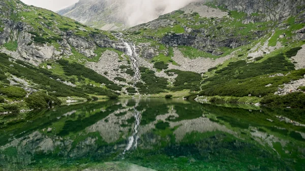 Górski strumień z widokiem na skaliste góry i jezioro z przezroczystą wodą — Zdjęcie stockowe