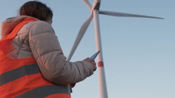 Un inspector de aerogeneradores de pie con tableta y controla el sistema. Generación de electricidad. — Vídeos de Stock