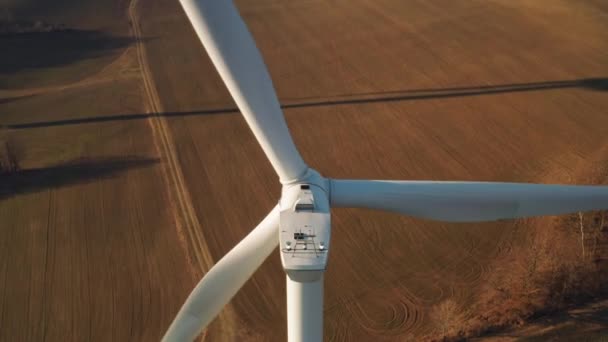 Cerrar una gran turbina eólica giratoria en el fondo del parque eólico al atardecer. — Vídeos de Stock